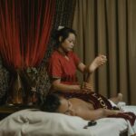A woman receives a therapeutic massage from a professional masseuse in a calming spa environment.