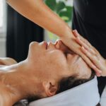 Woman receiving a calming face massage in a peaceful spa environment.