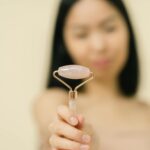 A woman holding a jade face roller, focusing on skincare and facial massage.