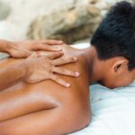 Person receiving a back massage outdoors, emphasizing relaxation and wellness.