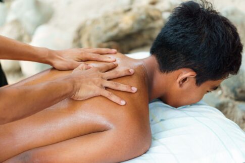 Person receiving a back massage outdoors, emphasizing relaxation and wellness.