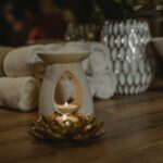 Serene spa setting with a lit candle, ceramic holder, and plush towels for relaxation.