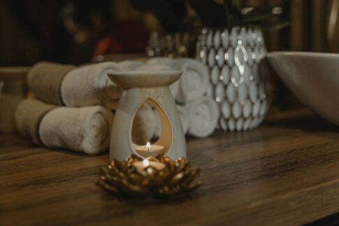 Serene spa setting with a lit candle, ceramic holder, and plush towels for relaxation.